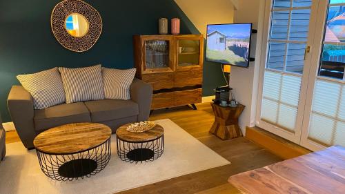 ein Wohnzimmer mit einem Sofa und einem TV in der Unterkunft Hotel Kiose - Ferienwohnungen in Wenningstedt-Braderup