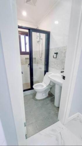 a white bathroom with a toilet and a sink at Trail Bedz Homestay in Baguio