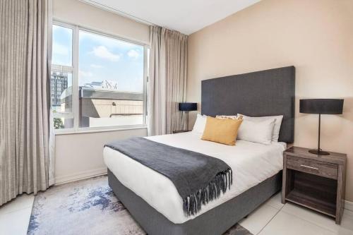 a bedroom with a large bed and a large window at Urban Oasis Apartments at Tyrwhitt in Johannesburg