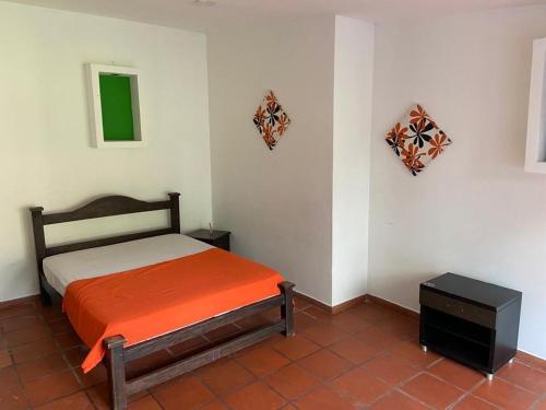 sypialnia z łóżkiem z pomarańczowym kocem w obiekcie Finca Villa juanes w mieście Villavicencio