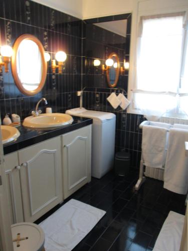 een zwart-witte badkamer met 2 wastafels en een toilet bij Les Milahinas in Lescure-dʼAlbigeois