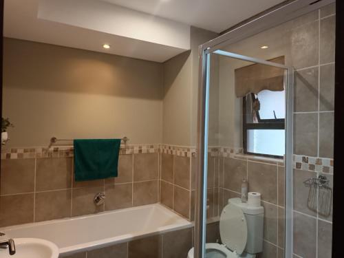a bathroom with a shower and a tub and a toilet at Apartment A8 inside Bains Lodge in Bloemfontein