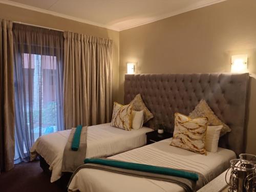 a hotel room with two beds and a window at Apartment A8 inside Bains Lodge in Bloemfontein