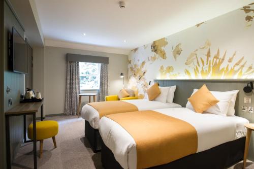 a hotel room with two beds and a desk at The Melville Inn by Innkeeper's Collection in Dalkeith