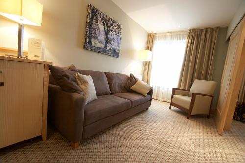 a living room with a brown couch and a chair at Lancaster House Hotel in Lancaster