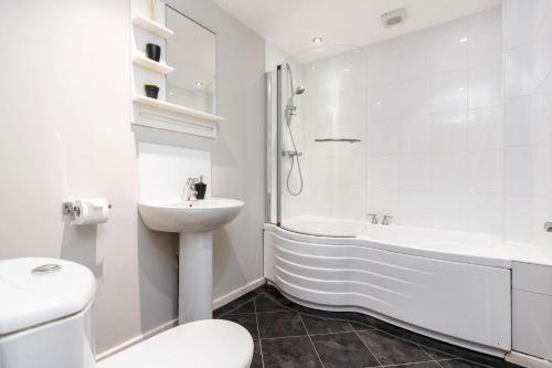 Stunning 3BD Home Hillsborough Sheffield في شيفيلد: حمام أبيض مع حوض وحوض استحمام ومرحاض