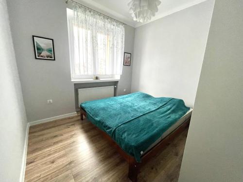 a bedroom with a green bed and a window at Apartament Jaskółka in Stronie Śląskie
