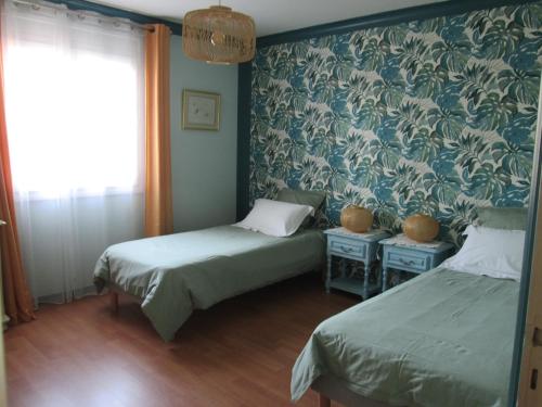 1 dormitorio con 2 camas y papel pintado azul y blanco en Les Milahinas en Lescure-dʼAlbigeois