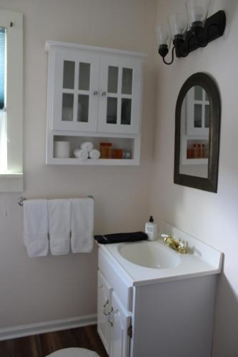 Baño blanco con lavabo y espejo en Cooperstown Bed and Breakfast en Cooperstown