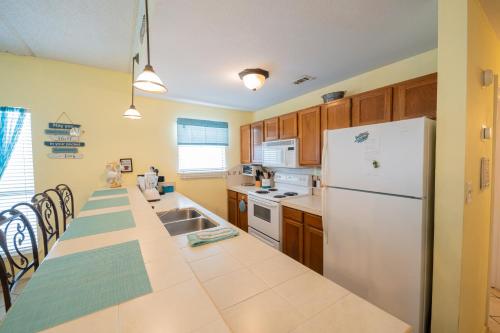 a kitchen with a white refrigerator and wooden cabinets at Affordable SPI family condo - walking distance to the beach, Sleeps 6, Third Floor, 2025 Traveler Award in South Padre Island