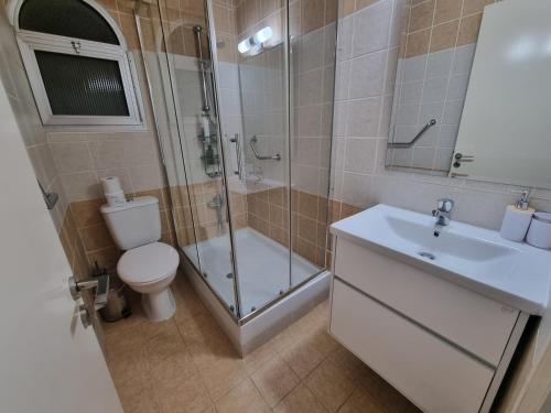 y baño con ducha, aseo y lavamanos. en Diamond Sea View Penthouse en Pafos