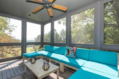 a screened in porch with blue furniture and windows at Laurel Lodge At Last in Townsend