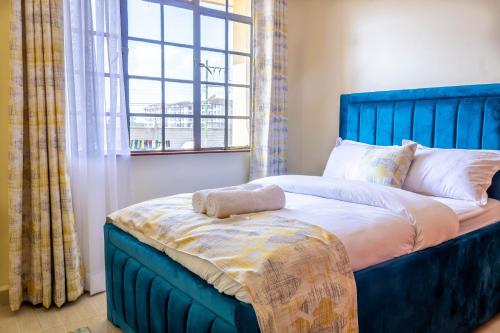 - un lit bleu dans une chambre avec fenêtre dans l'établissement Quzuri Homestay nearJKIA SGR NRB Kenya, à Syokimau