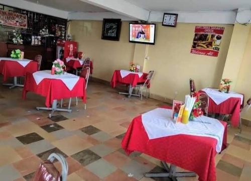ein Restaurant mit roten Tischen und Stühlen sowie einem TV in der Unterkunft Kakamega Town Guest House in Kakamega