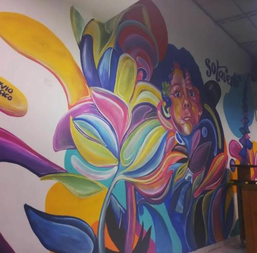 una pared con una pintura de una mujer con una flor en Casa Sotavento Cali, en Cali