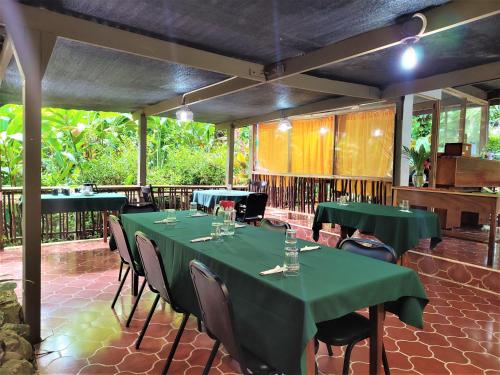 a restaurant with green tables and chairs in a room at Maya Mountain Lodge in San Ignacio