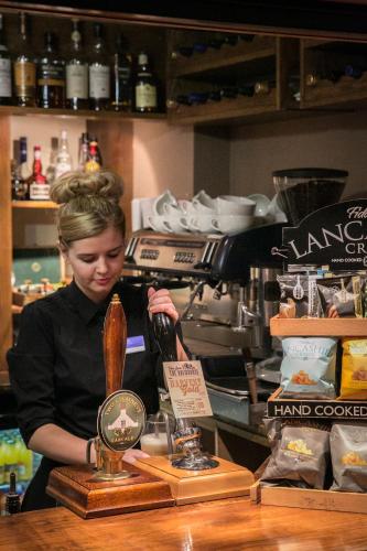 a woman standing behind a counter with a bottle of wine at Lancaster House Hotel in Lancaster