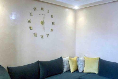 ein Wohnzimmer mit einem blauen Sofa und einer Uhr an der Wand in der Unterkunft Modern fully equipped two story appartement/duplex in Safi