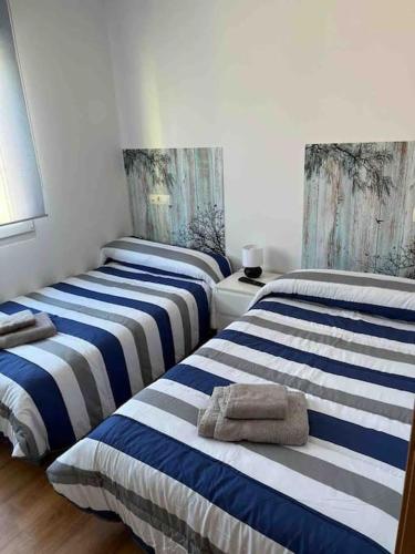 three beds in a room with blue and white stripes at Casa Toja. Agradable y familiar. in Vimianzo