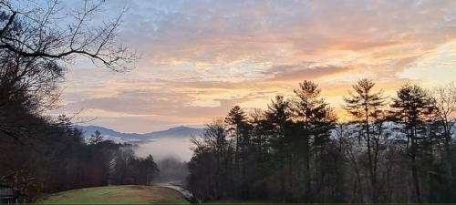 a sunset in the mountains with fog in the trees at Laurel Lodge At Last in Townsend