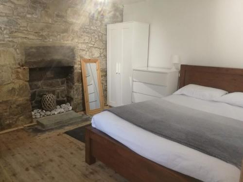 a bedroom with a bed and a stone fireplace at Kirtomy Cottage, Kirtomy, near Farr Beach, Bettyhill and Thurso in Farr