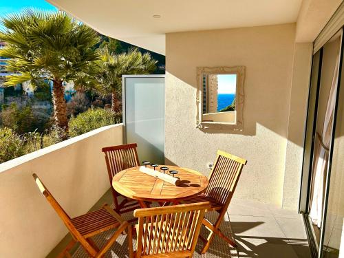 una mesa y sillas en un balcón con vistas al océano en Luxueux Studio Neuf - Frontière Monaco - Piscine - Parking privé en Montecarlo