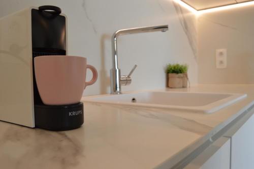 a coffee cup sitting on a counter next to a sink at Zeezicht vanop het 6 de verdiep in Oostduinkerke