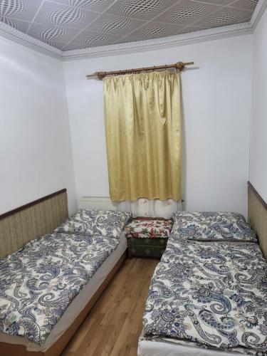 two beds in a room with a window at Almás vendégház in Tiszaújváros