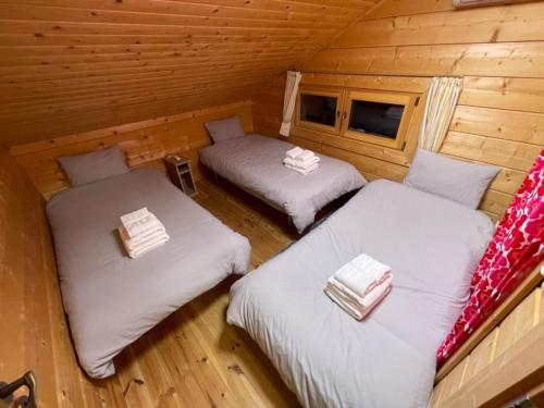 Duas camas num quarto com paredes de madeira em Polar House Karuisawa - Vacation STAY 30319v em Kutsukake