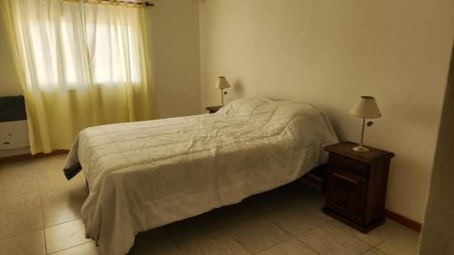 1 dormitorio con 1 cama y 1 mesa con lámpara en Departamento temporario Prado Español en San Nicolás de los Arroyos