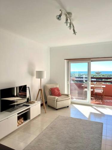 a white living room with a television and a couch at T3 beach front in São João da Caparica in Costa da Caparica