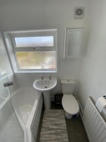 a bathroom with a toilet and a sink and a window at The Cosy House in Hugglescote