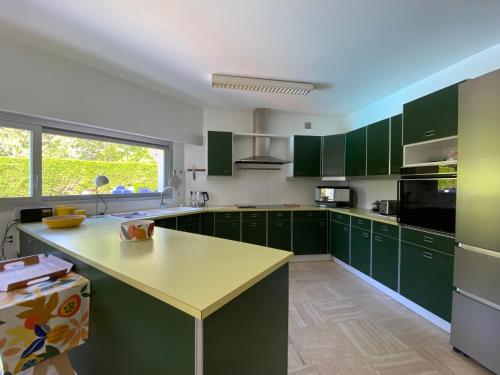 une cuisine avec des placards verts et un comptoir jaune dans l'établissement Villa 96 Golf de la Baule avec piscine et spa, à Saint-André-des-Eaux