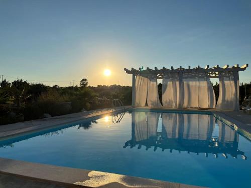 una piscina con cenador y puesta de sol en Casa California en Realmonte