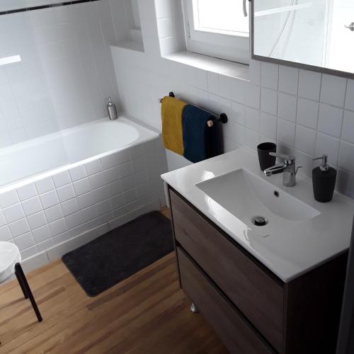 une salle de bain avec un lavabo blanc et une baignoire dans l'établissement MAISON DE VILLE AVEC GARAGE ET TERRASSE, à Lourdes