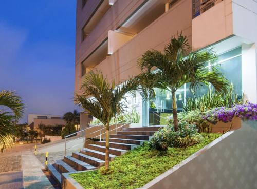 a building with stairs and palm trees in front of it at Atlantis Suites Bquilla -Apartamento Moderno-2-BD in Barranquilla