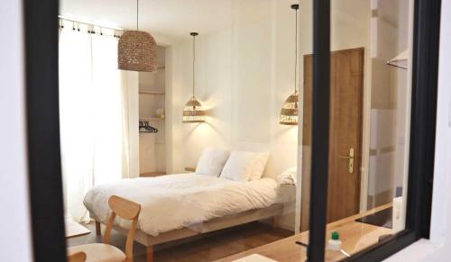 - une chambre avec un lit doté de draps blancs et d'un miroir dans l'établissement Charmant studio en plein coeur de Tain l'Hermitage, à Tain-lʼHermitage