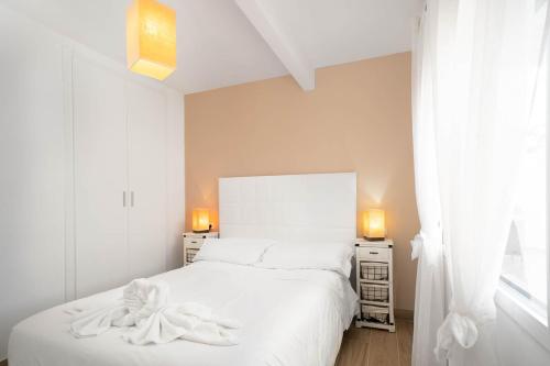 ein Schlafzimmer mit einem weißen Bett und zwei Nachttischen in der Unterkunft Ático La Barca by Paradise Gold Rentals in Benidorm