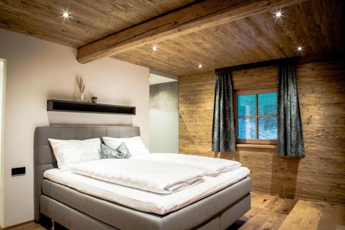 1 dormitorio con 1 cama grande y pared de madera en Müllner Appartements en Thiersee