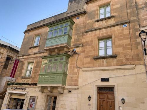 um grande edifício de tijolos com janelas verdes em GELMIF Apartments em Vittoriosa