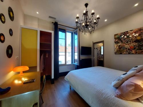 a bedroom with a bed and a chandelier at La Belle Epoque & Spa - Maison d'hôtes in Cournon-dʼAuvergne