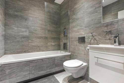 a bathroom with a toilet and a tub and a sink at No.1 Universal House - Double Bedroom Apartment in Bromley