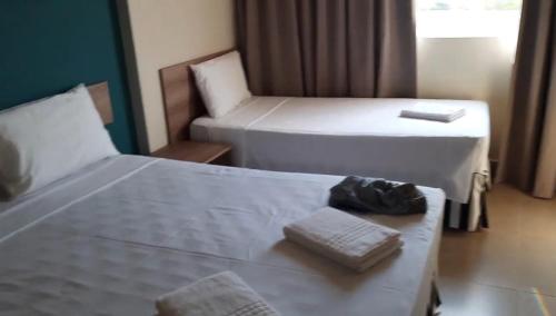 una stanza d'albergo con due letti e una sedia di Apto mobiliado - SOLAR DAS ÁGUAS - OLÍMPIA a Olímpia