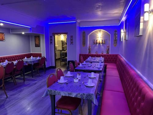 une salle à manger avec des tables, des chaises et un éclairage violet dans l'établissement Calypso hotel Blackpool, à Blackpool