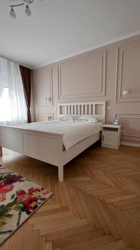 sypialnia z białym łóżkiem i drewnianą podłogą w obiekcie Charming Place Cotroceni w Bukareszcie