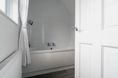 a white bathroom with a tub and a shower curtain at Lee House in Lynton