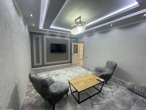 uma sala de estar com duas cadeiras e uma mesa e uma televisão em Light apartment em Tashkent