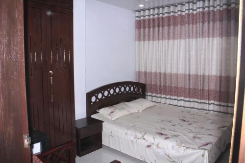 a small bedroom with a bed and a curtain at Private Bedroom in Lalmatia, Mohammedpur in Dhaka