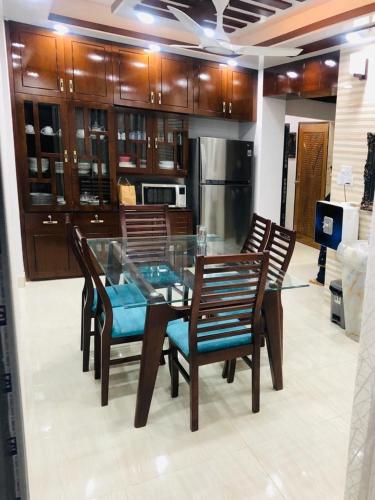 a kitchen with a glass table and wooden chairs at Private Bedroom in Lalmatia, Mohammedpur in Dhaka