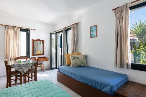 a bedroom with a bed and a table and window at Konaki Studios & Apartments in Panormos Rethymno